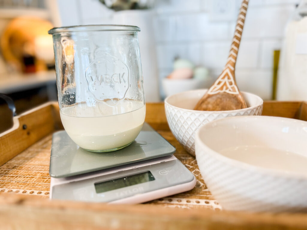 a Weck Jar sitting on top of a digital kitchen scale with sourdough starter and water inside the jar.